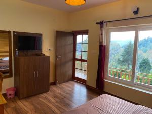 a bedroom with a television and a large window at Khushi Cottage in Mukteswar