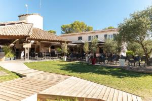 a walkway in front of a building with tables and chairs at Camping Les Prés du Roi in Sommières