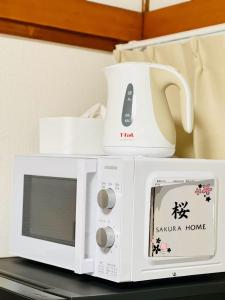 d'un four micro-ondes blanc avec une bouilloire. dans l'établissement 桜Home, à Tokyo