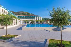 una gran piscina con un edificio y árboles en Admiral Grand Hotel, en Slano