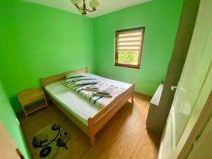 a bedroom with green walls and a bed with a window at Vila ILKA in Praid +9 photos