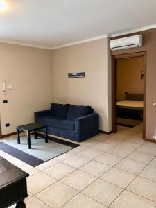 a living room with a blue couch and a bed at Valtidone Hotel in Borgonovo Val Tidone