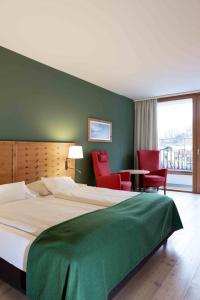a bedroom with a large bed and red chairs at SPA Hotel Erzherzog Johann in Bad Aussee
