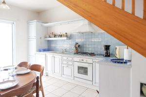 eine Küche mit weißen Schränken und einem Tisch mit einem Esszimmer in der Unterkunft Spacieuse maison avec extérieur quartier Arago Les Sables 7 personnes in Les Sables-dʼOlonne + 7 Fotos