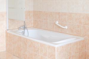 eine Badewanne im gefliesten Bad in der Unterkunft Spacieuse maison avec extérieur quartier Arago Les Sables 7 personnes in Les Sables-dʼOlonne