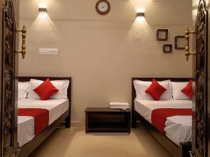 two beds in a room with red pillows at Rudra Villas in Rāmeswaram