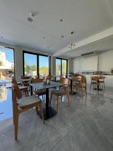 a dining room with tables and chairs and windows at Catherine Hotel in Kos