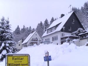 a house covered in snow with a sign in front at Spacious apartment in Rattlar with private terrace in Willingen