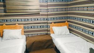 zwei Betten in einem Zimmer mit einer Wand in der Unterkunft Dana Village Lodge in Dana