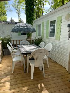 une table et des chaises avec un parasol sur une terrasse dans l'établissement mobil home 6 personnes situé à 15 mn d europa park et rulantika, à Boofzheim