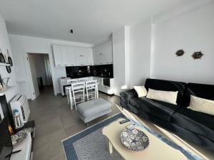 a living room with a black couch and a kitchen at SoleMar Suites in Vlorë