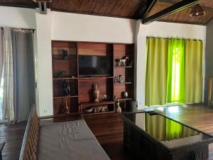 - un salon avec une télévision et un rideau vert dans l'établissement blue fenix, à Mahavelo