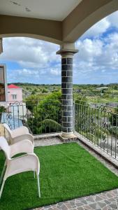 a porch with two white chairs and green grass at Cozy Apartment with Pool & 10 mins walk to Beach in Mont Choisy +3 photos
