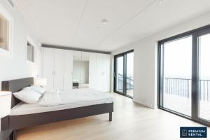 a white bedroom with a bed and large windows at C44 Ultimate Luxury Waterfront Penthouse in Hanko