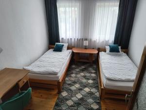 a room with two beds and a table and a window at Apartament Pod Orzechem in Augustów