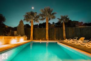 een zwembad met stoelen en palmbomen in de nacht bij Villa Baladrar Way by Abahana Villas in Benissa