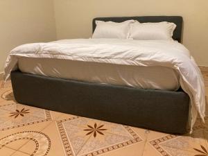 a bed with a black foot board on top of it at Jinja Airport apartment in Jinja