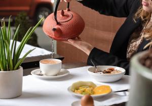 a woman holding a tea pot over a table with food at Jade Manotel in Geneva