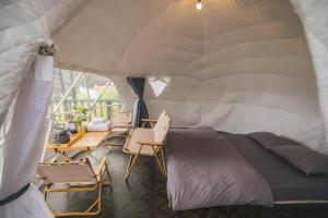 a room with a bed and chairs in a tent at Lavender Dalat Hotel and Resorts in Da Lat