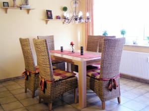 einen Esstisch mit Korbstühlen sowie einem Tisch und einem Chairsktop in der Unterkunft Wellness-Ferienwohnung Strandperle in Cuxhaven