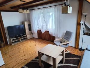 a living room with a tv and a chair and a table at Apartament Pod Orzechem in Augustów