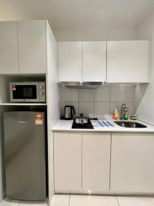 a white kitchen with a refrigerator and a microwave at The Urban Left at Horizon Suites KLIA in Kampong Melot