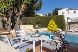 un patio con mesa y sillas junto a una piscina en Villa Baladrar by Abahana Villas, en Benissa