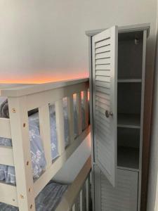 ein weißes Etagenbett mit einem Bücherregal neben einem Kinderbett in der Unterkunft Sandy Beach Hill View Apartment Brean in Brean
