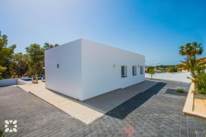 a white building on a brick road with palm trees at Villa Baydal by Abahana Villas in Benissa