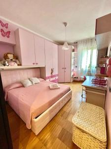 a bedroom with a pink bed and a table at Beatrice Apartment in Massa