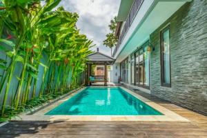 una piscina en el patio trasero de una casa con plantas en White 2 BR Private Pool Villa AN02, en Canggu
