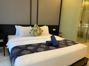um quarto com uma cama grande com lençóis brancos e almofadas em Tropicana The Residences By RS em Kuala Lumpur