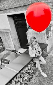 una chica sentada en un banco con un globo rojo en Les chambres atypiques de Nico Bush - Parking sécurisé vélos en Tournai
