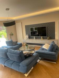 ein Wohnzimmer mit 2 blauen Sofas und einem TV in der Unterkunft Villa luxueuse in Allonnes