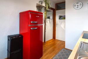 a red refrigerator in a room with a clock on the wall at Ferienwohnung KARKER 2 in Radolfzell am Bodensee