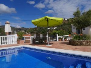 een patio met een parasol en een zwembad bij Cortijo Pura Vida in Cómpeta