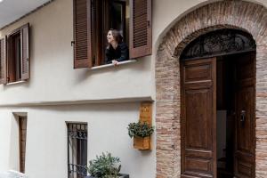 a woman looking out the window of a house at B&B Vico Suites in Vico nel Lazio