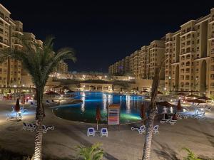 a swimming pool with palm trees and buildings at night at 5 stars Studio Aqua View North coast in Borg El Arab