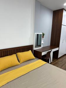 1 dormitorio con cama con almohadas amarillas y escritorio en Happy House en Hanói