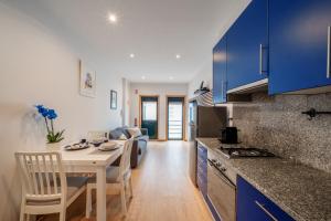 a kitchen with blue cabinets and a table with chairs at Beira Mar Sunny Patio in Aveiro