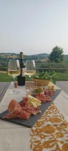 Poderino - a place to feel في Cento: طاولة مع كأسين من النبيذ الأبيض والطعام