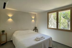 una camera da letto con un letto bianco e una finestra di Sète - Maison entière et jardin sur le Mont Saint Clair - vue mer et étang a Sète