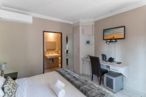 um quarto com uma cama e uma secretária com um computador em Villa Africa Boutique Hotel & Spa em Pretoria