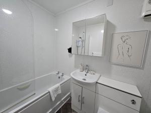 een witte badkamer met een wastafel en een spiegel bij Sensational Stay at South Bridge in Edinburgh