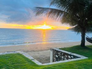 Badladz Beach and Dive Resort في بويرتو غاليرا: غروب الشمس على الشاطئ مع نخلة
