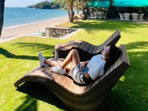 a woman laying on a bench next to the beach at Badladz Beach and Dive Resort in Puerto Galera