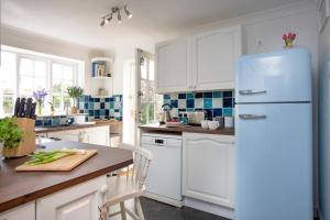 eine Küche mit weißen Schränken und einem blauen Kühlschrank in der Unterkunft Peacehaven Cottage - Sidmouth in Sidbury