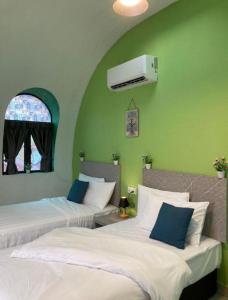 two beds in a room with green walls at Mamee Dome Villa Best Homestay in Kampong Alor Gajah