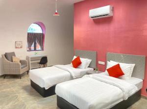 a bedroom with two beds and a red wall at Mamee Dome Villa Best Homestay in Kampong Alor Gajah
