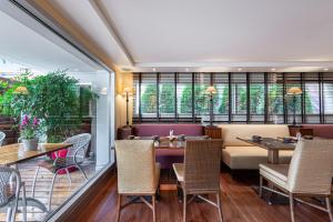 a restaurant with tables and chairs and windows at Kipling Manotel in Geneva